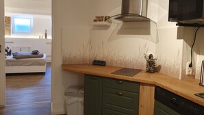 Une cuisine moderne dotée d’un plan de travail en bois, de meubles de rangement verts, d’un lave-vaisselle Bosch et d’une hotte de cuisine en acier inoxydable.