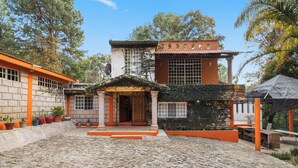 A courtyard with a stone floor, a central archway, and a building with a tiled roof and orange accents. - Family Chalet in Villa Vicente 4 BR (Villa Guerrero)