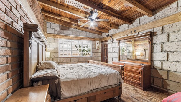 A rustic bedroom with exposed brick walls, a wooden ceiling, and a large bed. - Family Chalet in Villa Vicente 4 BR (Villa Guerrero)
