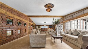A spacious living room with a brick wall, a large sofa, a smaller armchair, and a coffee table. - Family Chalet in Villa Vicente 4 BR (Villa Guerrero)