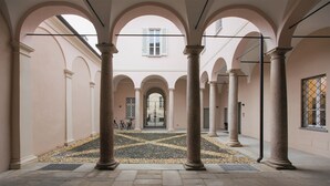 Une cour intérieure avec des colonnes, un sol carrelé et une porte visible au fond.