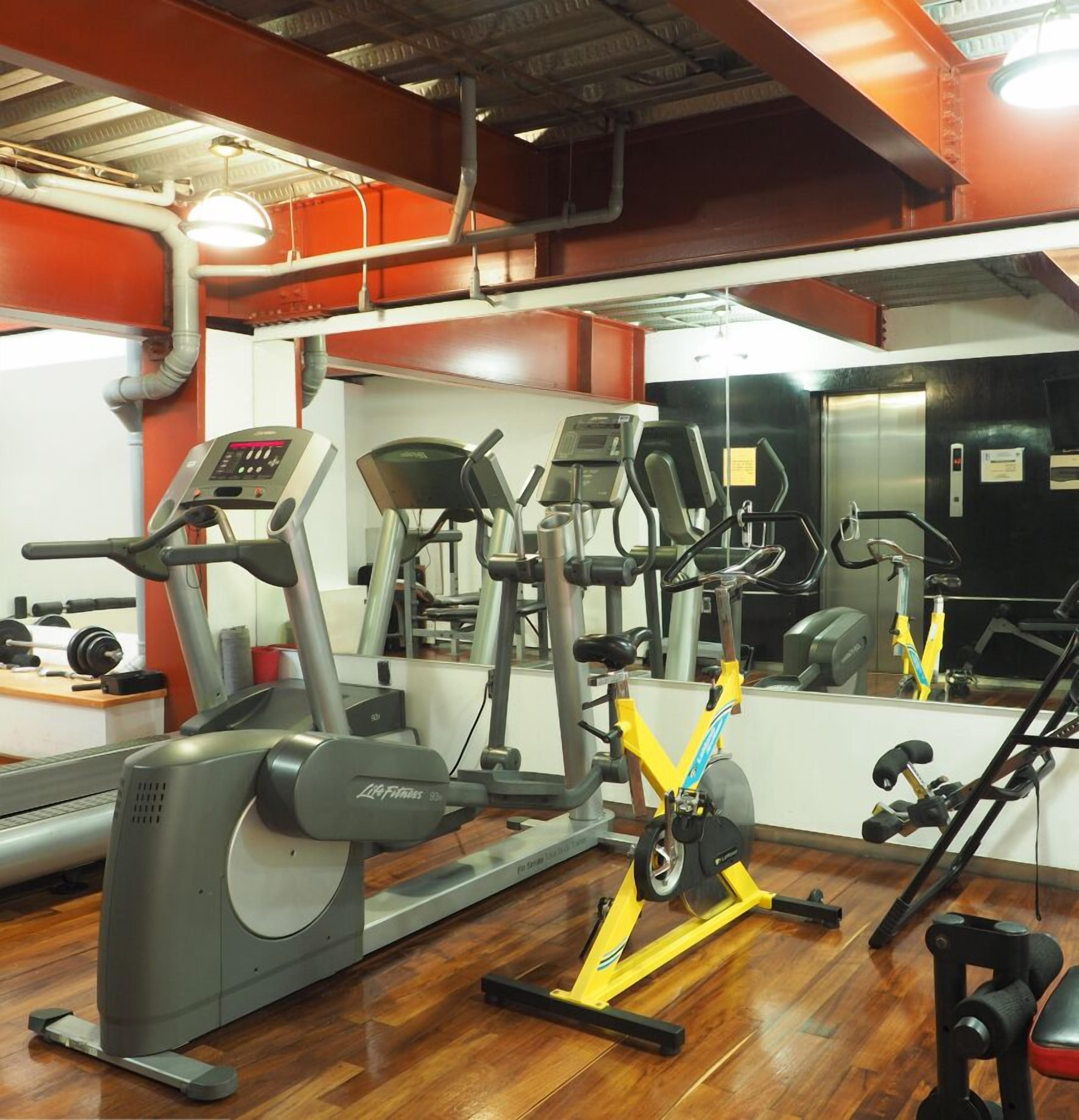 A gym with various exercise equipment including treadmills, stationary bikes, and weight machines.