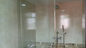 Een moderne badkamer met een douchecabine van glas, een witte wastafel en behangtegels op de wanden.