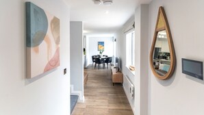 A hallway with a dining area, a mirror, and a staircase.