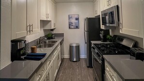 A modern kitchen with white cabinets, stainless steel appliances, and a central island. - Oasis 2 BR View of Hollywood Sign, W/D, & Parking (Los Angeles)