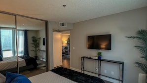 A modern bedroom with a large bed, a TV, and a mirror. - Oasis 2 BR View of Hollywood Sign, W/D, & Parking (Los Angeles)