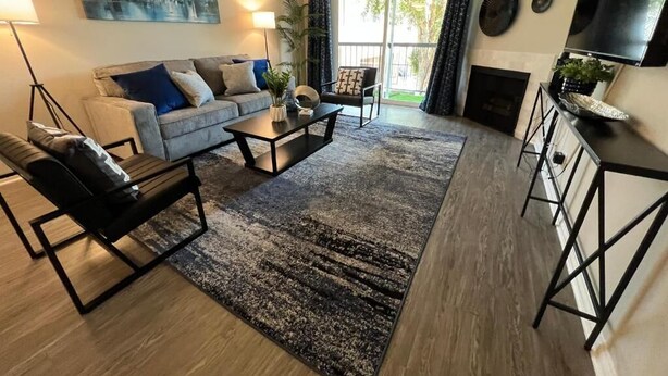 A modern living room with a sofa, coffee table, and a TV. There is a fireplace and a large window with curtains. - Oasis 2 BR View of Hollywood Sign, W/D, & Parking (Los Angeles)