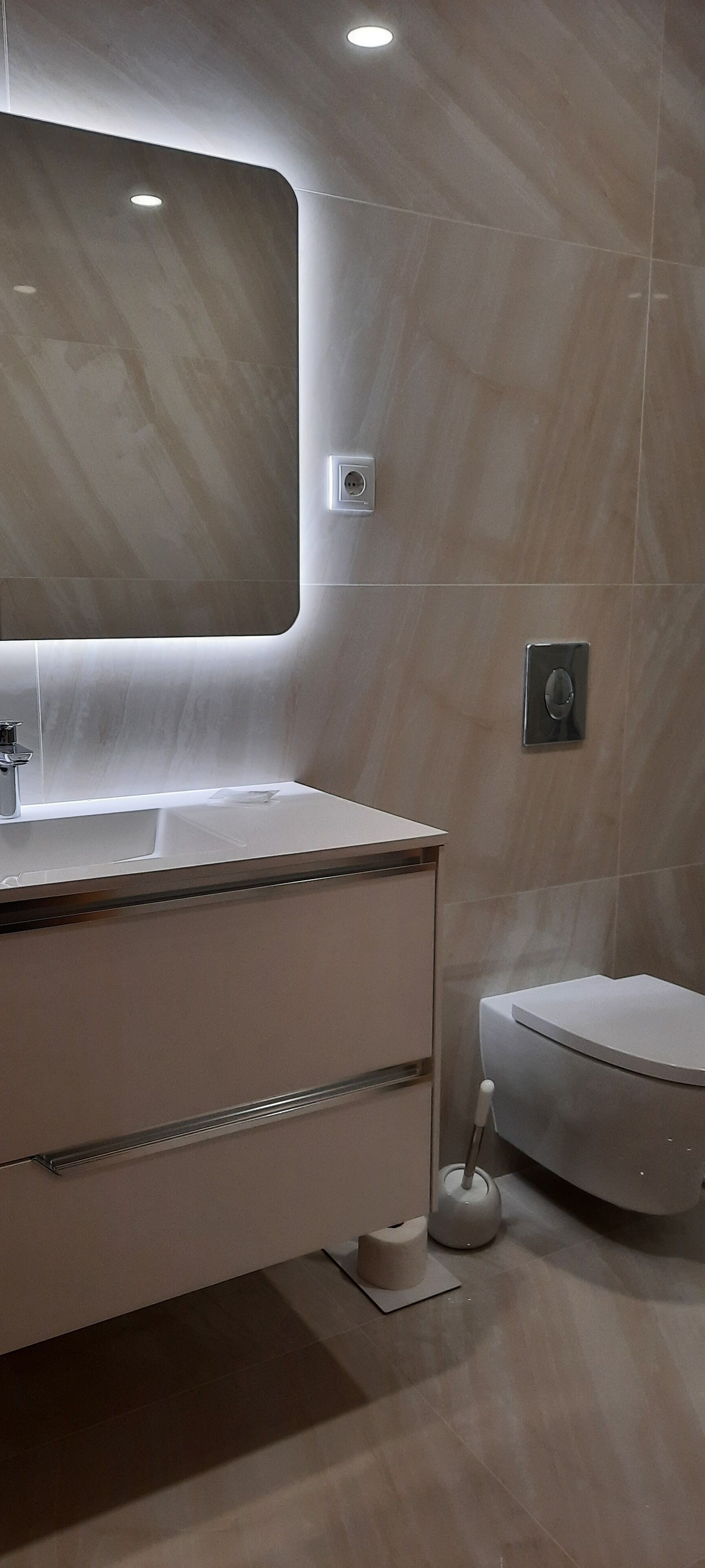 Un baño moderno con lavamanos de mármol, un espejo y un inodoro.