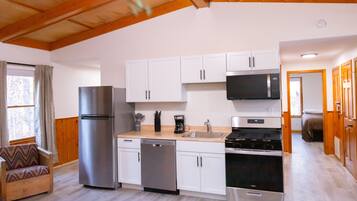 A modern kitchen with white cabinets, stainless steel appliances, and a wooden ceiling.