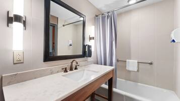 A bathroom with a marble sink, a large mirror, a shower with a curtain, and a towel rack.