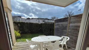 A patio with a round table and chairs, a wooden deck, and a view of a residential area with houses and a hedge. - 3-room 2-bedroom apartment close to the ramparts of Vannes (Vannes)