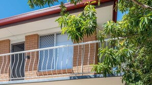 Un balcone con ringhiera metallica, tetto rosso e parete in mattoni.