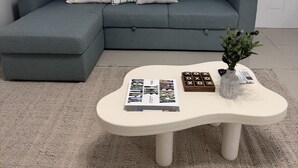 A modern living room with a grey sectional sofa, a white coffee table, and a small plant. - Charming 1-bedroom apartment in North Bay Village with WiFi, AC (North Bay Village)