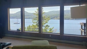 A room with large windows offering a view of a lake and mountains. - Waterfront View Rosario Sleeps 10- (Eastsound)