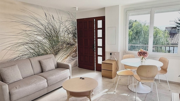 A modern living room with a sofa, a round coffee table, and a dining area with chairs and a small table.