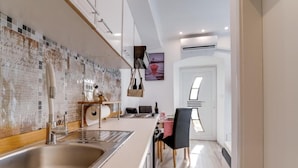 A modern kitchen with a large island, stainless steel sink, and a backsplash with mosaic tiles. - Antigona (Bakar)
