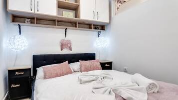 Un dormitorio con cama, mesitas de noche, armario e iluminación en la pared.
