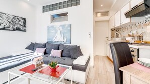 A modern living room with a sofa, a glass coffee table, and a painting of a sailboat. - Antigona (Bakar)