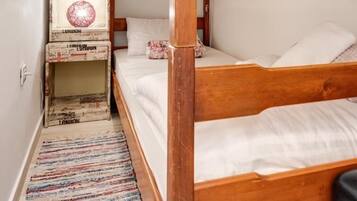 A bunk bed with white bedding and a wooden headboard.