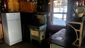 Une cuisine avec des meubles en bois, un réfrigérateur blanc, une cuisinière et une fenêtre donnant sur un paysage enneigé.