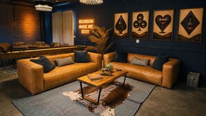 Un espace salon confortable avec des canapés en cuir, une table basse et des œuvres d’art murales.