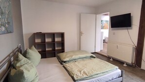 Une chambre à coucher avec un lit, une étagère en bois, un radiateur et un téléviseur fixé au mur.