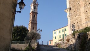 Una escalera de piedra histórica conduce a una torre campanario, flanqueada por edificios de arquitectura tradicional.
