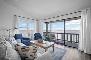 A living room with a sofa, chairs, a coffee table, and a view of the sea through large windows. - Couples Retreat with Breathtaking Oceanfront Views, Community Pool, Elevator - 735 North Hampton (Fripp Island)