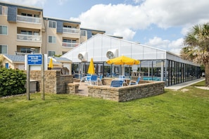 A poolside area with lounge chairs and umbrellas, a sign indicating children under 12 must be accompanied by parents, and a building with balconies.