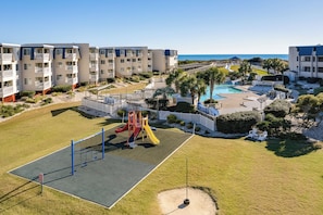 A residential area with a playground, a swimming pool, and a beach view.