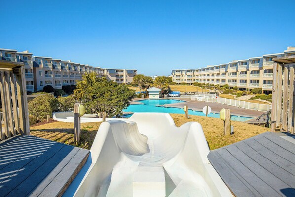 A view of a resort with a pool, a slide, and multi-story buildings.