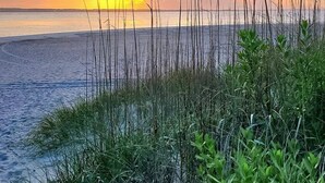A beach with tall grasses in the foreground and a sunset over the water. - A Place at the Beach - 2 bedroom, 2 baths - Pools, Waterslide, Mini-golf & more! (Atlantic Beach)