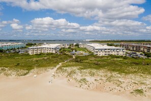 Ett hotell vid kusten med flera byggnader, en strand och en klar himmel.