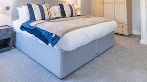 Een slaapkamer met een groot bed, nachtkastjes, een kledingkast en wandlampen.