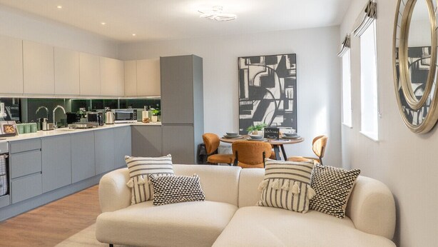 Een moderne woonkamer met een hoekbank, een glazen salontafel en een eethoek met een tafel en stoelen.