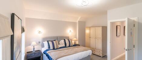 A bedroom with a bed, bedside tables, a wardrobe, and a door.