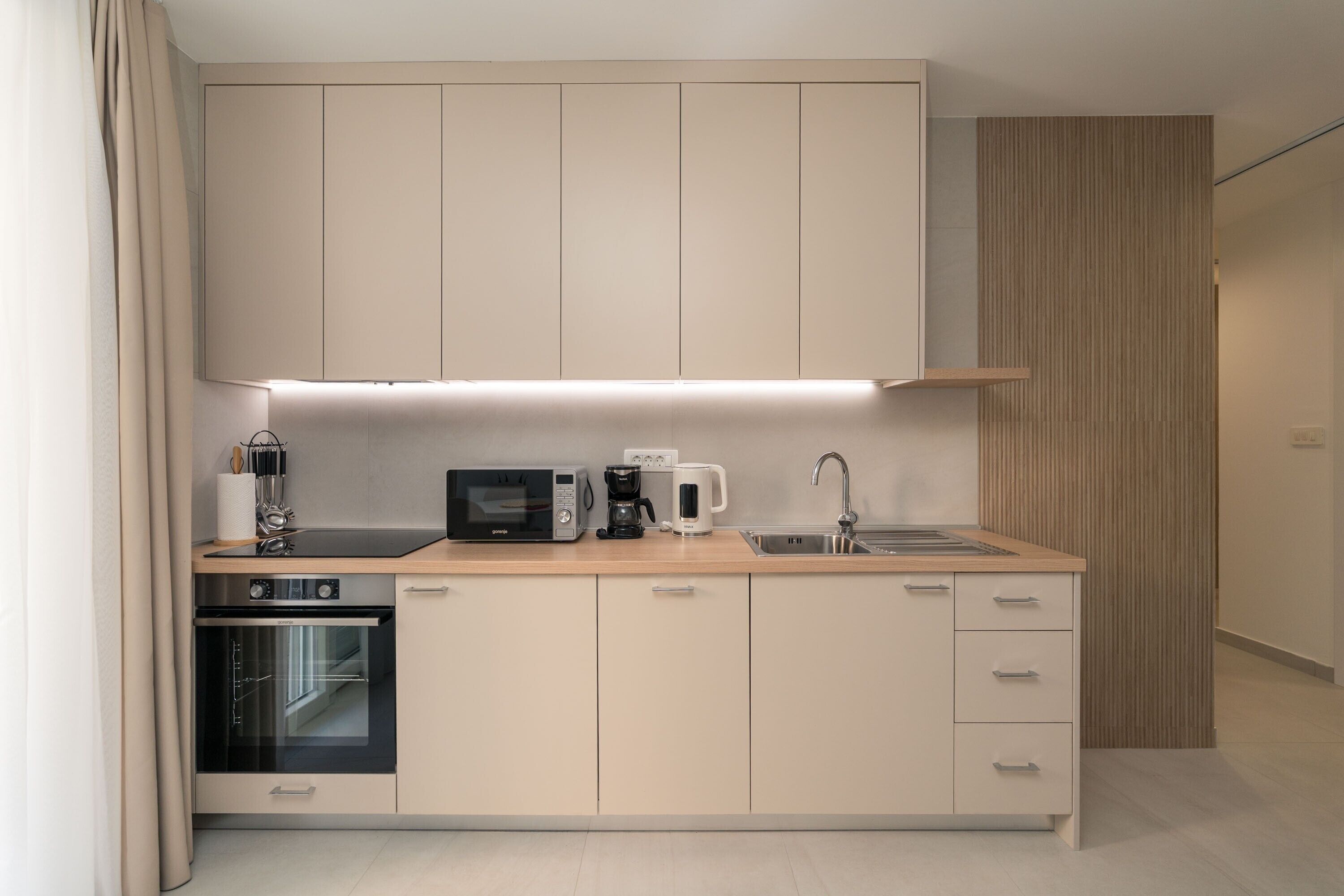 A modern kitchen with a microwave, coffee maker, and oven.