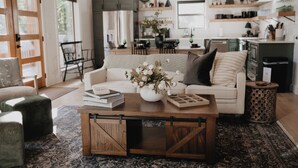 Een moderne woonkamer met een witte bank, een bijzettafeltje met een bloevas, en een rustieke houten salontafel.