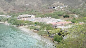 A coastal village with houses on a hillside, a beach, and a body of water. - Paraiso Casa de Playa (Taganga)