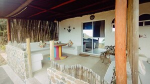 A covered outdoor area with a stone wall, a colorful table, and a window with a view. - Paraiso Casa de Playa (Taganga)