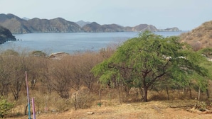A natural landscape with a body of water, hills, and sparse vegetation. - Paraiso Casa de Playa (Taganga)