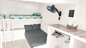 A compact room with a bed, a desk, a fan, and a laundry rack. - Paraiso Casa de Playa (Taganga)