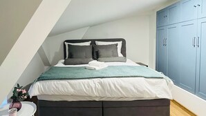 Een slaapkamer met een bed, een klein tafeltje, een stoel en een kledingkast.