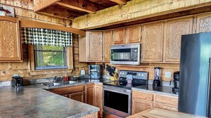 A kitchen with wooden cabinets, a microwave, a stove, a refrigerator, and a sink. - A Bear’s Eye View – Epic 4BR 3BA Cabin wGame Room, Hot Tub & Stunning Vistas!  (Sevierville)