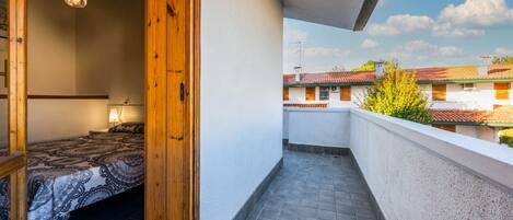 Un balcón con suelo de baldosas y vista a edificios vecinos.