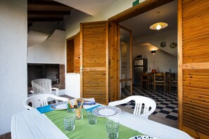 A dining area with a table set for four, surrounded by white chairs, a green table runner, and a patterned tablecloth. - Resort With Shared Garden and Swimming Pool (San Michele al Tagliamento)