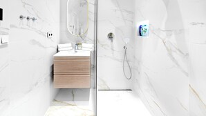 Une salle de bain moderne avec des murs en marbre, un meuble-lavabo en bois, une cabine de douche en verre et une douchette à main.
