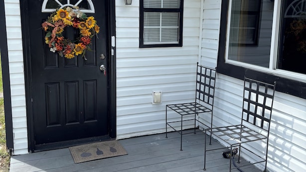 A house with a black front door, a wreath, a small window, and a metal bench on the porch. - Charming 2-bedroom house with WiFi, AC in beautiful Gulf Breeze (Gulf Breeze)