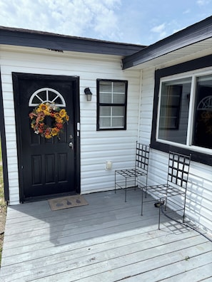 Welcome to this charming home with a cozy porch featuring a decorative wreath, shutters, and a bench.