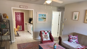 A living room with a blue coffee table, a red armchair, a beige sofa, and a patterned rug. - Charming 2-bedroom house with WiFi, AC in beautiful Gulf Breeze (Gulf Breeze)